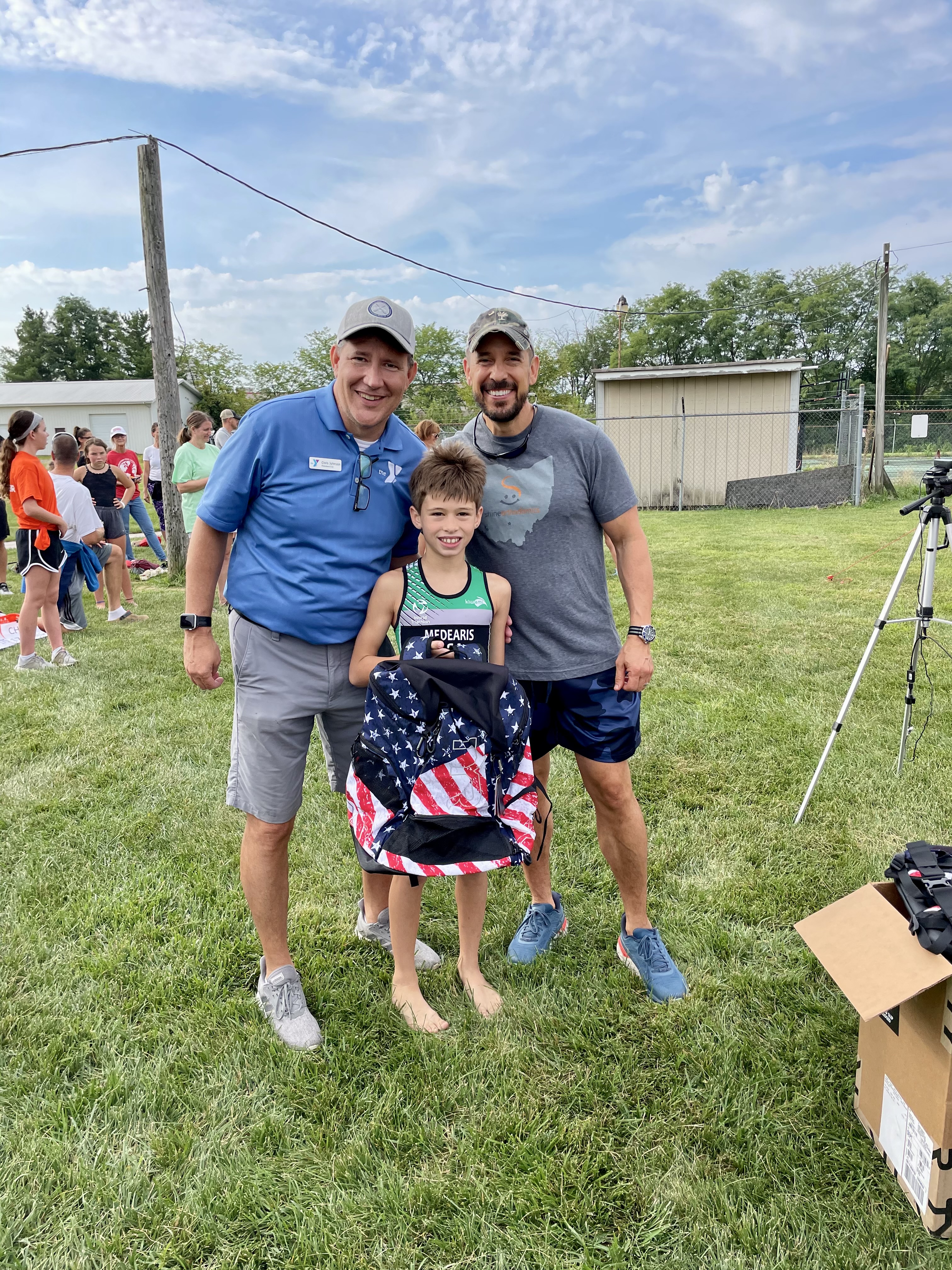 Two men smiling with boy holding bag 